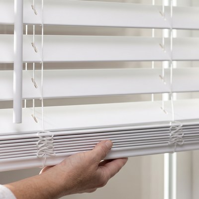 Hand operating the cordless lift on a Faux Wood Blind