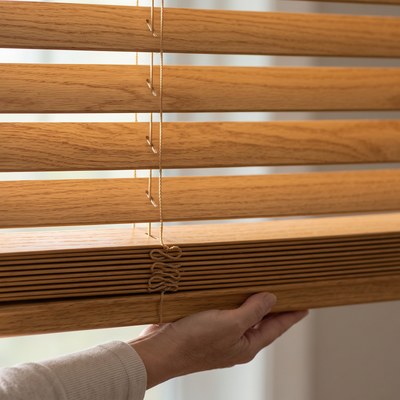 Hand operating the cordless lift on a Wood Blind